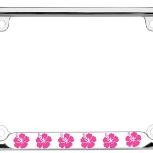 May include: Chrome license plate frame with palm tree and hibiscus flower accents. The frame features a polished chrome finish with detailed palm tree designs at the corners. The bottom of the frame has a white stripe with pink hibiscus flowers.