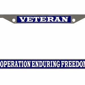 May include: A silver-colored license plate frame with the word "VETERAN" in white capital letters on a blue background at the top. The bottom of the frame has the text "OPERATION ENDURING FREEDOM" in white capital letters on a blue background.