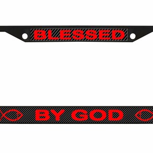 May include: Black license plate frame with the words "BLESSED" and "BY GOD" in red. The text is on a black and gray striped background. Red fish symbols are on each side of the bottom text.