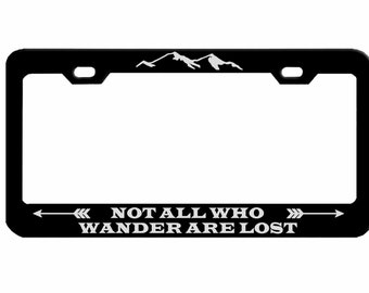 May include: Black metal license plate frame with a white mountain range design and the text "NOT ALL WHO WANDER ARE LOST" with arrows on either side.