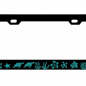 May include: Black license plate frame with a teal sea turtle and ocean life design. The frame features a border of sea turtles, starfish, and coral. The license plate frame is rectangular and has mounting holes.