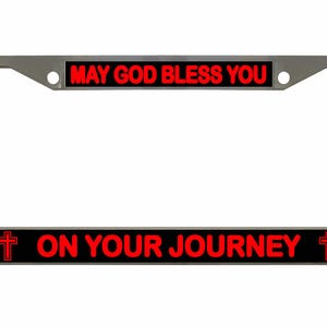 May include: A chrome license plate frame with the text "MAY GOD BLESS YOU" at the top and "ON YOUR JOURNEY" at the bottom in red letters. Red crosses are on each end of the bottom text.