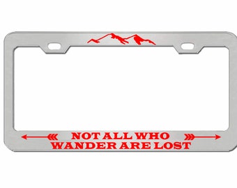 May include: Silver license plate frame with a red mountain range graphic and the text "NOT ALL WHO WANDER ARE LOST" with red arrows on either side.