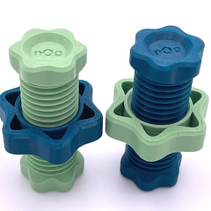 May include: Two 3D printed star-shaped knobs, one green and one blue, with the word "MOC" printed on the top. The knobs are stacked on top of each other.