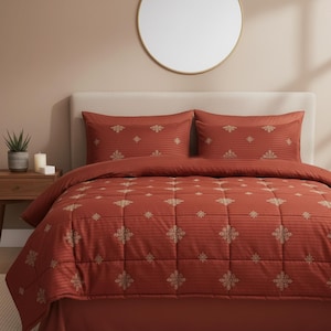 以下が含まれることがあります： 模様入りの錆色のベッドセット。セットには、掛け布団、枕カバー2枚、ベッドスカートが含まれます。掛け布団と枕カバーには、繰り返しの金色の花柄があります。ベッドはニュートラルカラーの壁に面しています。