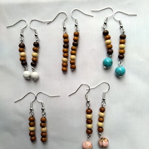 May include: Four pairs of wooden bead earrings. Two pairs feature white beads, one pair features turquoise beads, and one pair features pink beads.