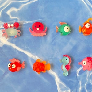 May include: A set of eight colorful bath toys shaped like sea creatures. The toys include a crab, an octopus, a fish, a seahorse, and a few other sea creatures. The toys are made of a soft, squishy material and are perfect for bath time fun.