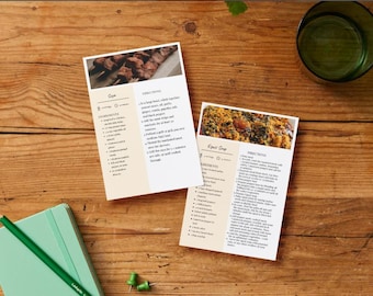 Könnte beinhalten: Zwei Rezeptkarten mit Essensbildern und Text liegen auf einem Holztisch. Eine Karte trägt den Titel "Sopa" und die andere "Equest Soup". Ein grünes Notizbuch, ein Bleistift, Reißzwecken und ein Glas Wasser liegen ebenfalls auf dem Tisch.