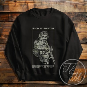May include: Black sweatshirt with a graphic of a sloth wearing military gear and holding a rifle. The text "Slow is Smooth, Smooth is Fast" is printed on the sweatshirt.