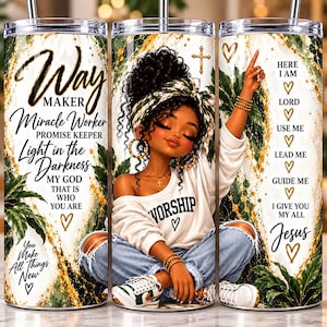 May include: A cylindrical tumbler featuring a graphic of a person with curly hair wearing a white shirt with the word WORSHIP, blue jeans, and sneakers. The design includes green leaves, gold accents, and text including Way Maker, Miracle Worker, and Here I Am Lord.