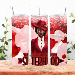 May include: A red and white tumbler featuring three illustrations of women in hats and suits. The central image shows a woman in a red suit and hat. The text "THERE IS STRENGTH IN SISTERHOOD" is displayed in black and red.