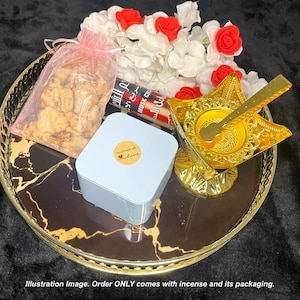 May include: A black and gold tray with a white box, a bag of nuts, and a gold incense burner with a spoon. The tray has a marble pattern. The box has a sticker that says "Handmade with Love".