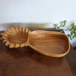 May include: A wooden pineapple-shaped serving bowl with two sections. The bowl is made of light brown wood and has a natural finish.