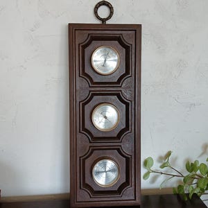 Puede incluir: Una taza de cerámica blanca con un asa negra y el texto "But First, Coffee" en negrita negra. La taza está sobre una superficie de madera. La taza mide aproximadamente 10 cm de alto.