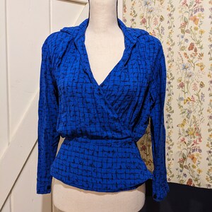 May include: A blue and black patterned wrap blouse with long sleeves and a V-neckline.