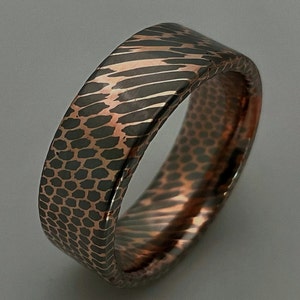May include: A wide copper band ring with a textured, hammered finish. The ring has a dark brown and copper color.