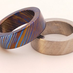 May include: Two rings, one with a blue and gold patterned finish and the other with a brushed silver finish.