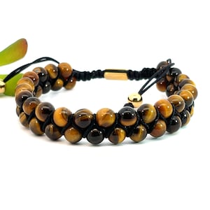 May include: A double-row bracelet made with tiger's eye beads and black cord. The bracelet has a gold-tone clasp and adjustable cord.