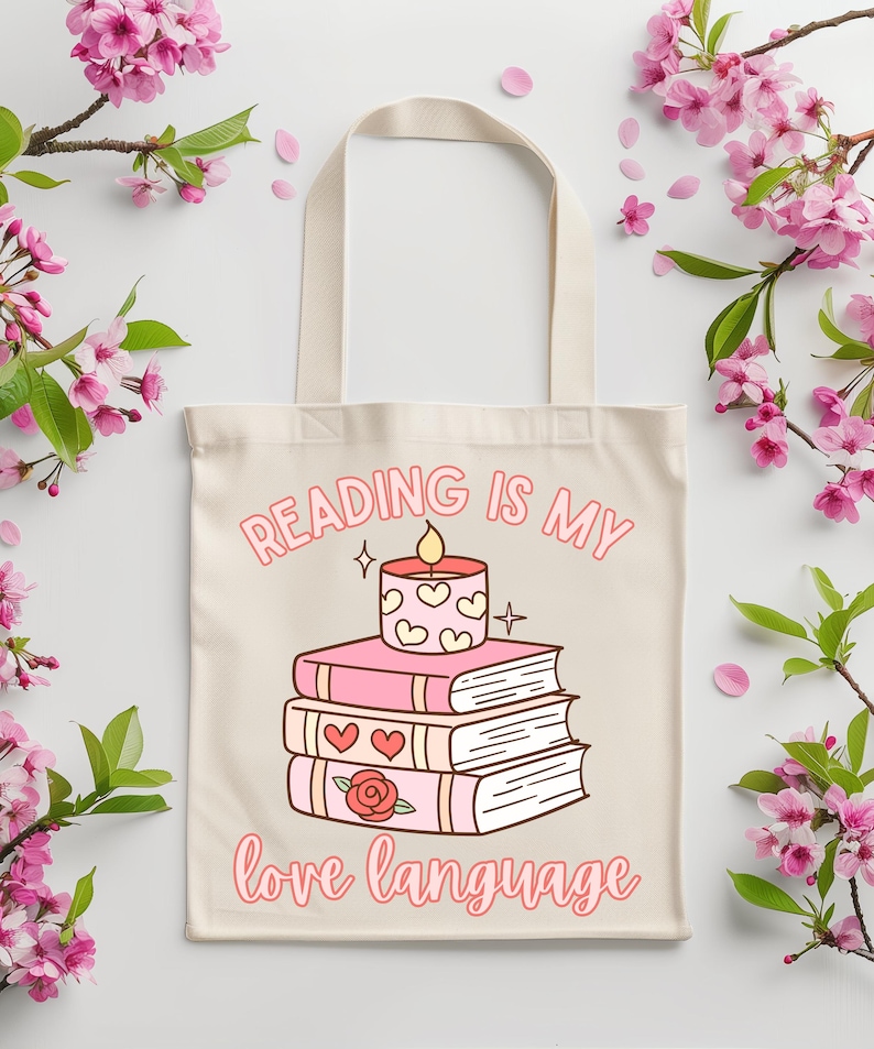 Op de afbeelding: Een witte tote bag met een roze en wit ontwerp. De tas heeft een stapel boeken met een brandende kaars erop. De tekst op de tas is "Reading is my love language".