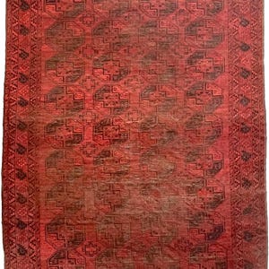 May include: A rectangular, red rug with a repeating geometric pattern in dark brown and black. The rug features a central field of octagonal shapes and a detailed border design. The rug's color palette includes shades of red, brown, and black.