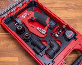 May include: A red Milwaukee Fuel cordless drill system housed in a red plastic carrying case with a clear lid. The set includes a drill body, multiple interchangeable chuck attachments, a battery pack, and an assortment of small metal drill bits.