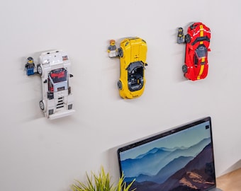 May include: Three wall-mounted display shelves, each featuring a small plastic minifigure standing on a ledge next to a toy sports car. The cars are white, yellow, and red, and each is securely attached to the wall in a vertical orientation.