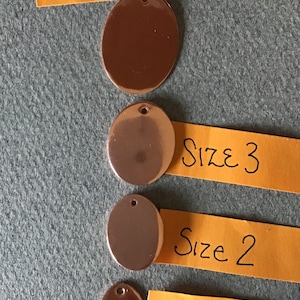 May include: Four round copper discs of varying sizes, labeled "Size 4", "Size 3", "Size 2", and "Size 1" on yellow paper.
