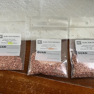 May include: Three clear plastic bags filled with small copper bits and scraps. Each bag has a label that reads "Quail Run Findings" and includes information about the copper bits, including the size and weight. The label also includes the word "Quan:" followed by a blank line.