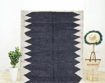 May include: A black and white Moroccan rug with a geometric pattern. The rug has a fringe border and is made of wool.