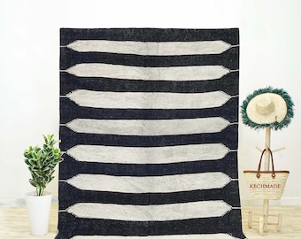 May include: Black and white striped rug with a fringe border. The rug has a geometric pattern with pointed ends on each stripe.