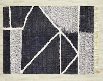 May include: Black and white geometric patterned rug with a fringe border. The rug has a modern design with a black background and white lines.