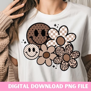 Peut inclure: Un t-shirt blanc avec un motif graphique brun, noir et blanc repr&eacute;sentant un visage souriant, une fleur &agrave; carreaux, une fleur &agrave; imprim&eacute; l&eacute;opard et une fleur avec un centre brun.