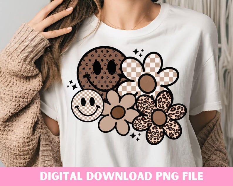 Peut inclure: Un t-shirt blanc avec un motif graphique brun, noir et blanc repr&eacute;sentant un visage souriant, une fleur &agrave; carreaux, une fleur &agrave; imprim&eacute; l&eacute;opard et une fleur avec un centre brun.