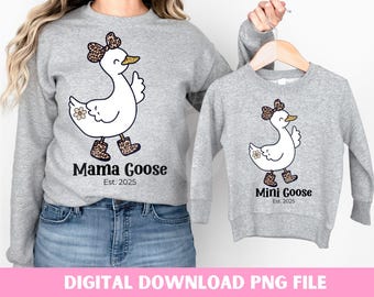 Può includere: Due felpe grigie con un design a forma di oca. La felpa più grande dice "Mama Goose Est. 2025" e la felpa più piccola dice "Mini Goose Est. 2025".