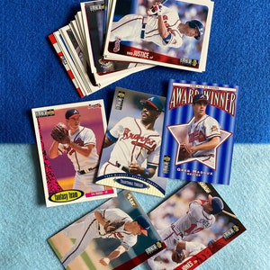 May include: A collection of baseball trading cards featuring Atlanta Braves players. The cards are from the 1995 season and feature players like Greg Maddux, David Justice, and Chipper Jones. The cards are in good condition and would be a great addition to any baseball card collection.