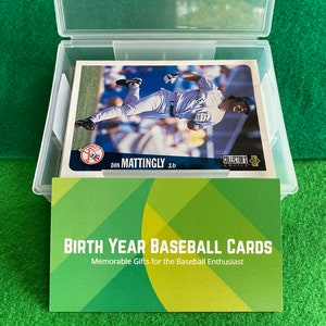 May include: A clear plastic storage box with a green background. The box contains baseball cards with a green, white, and yellow design. The text on the card reads "Don Mattingly 1b" and "Collector's Choice". The text on the front of the box reads "Birth Year Baseball Cards" and "Memorable Gifts for the Baseball Enthusiast".