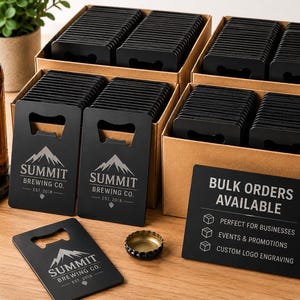 Puede incluir: Abrebotellas negros con el logotipo y texto "SUMMIT BREWING CO.", apilados en cajas de cartón. Un letrero dice "BULK ORDERS AVAILABLE" con texto sobre negocios, eventos y grabado de logotipo personalizado. También se ve una chapa.