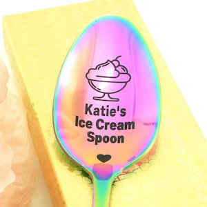 May include: A rainbow iridescent stainless steel spoon with a black ice cream cone graphic and the text "Katie's Ice Cream Spoon" with a small heart.
