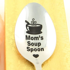May include: A stainless steel soup spoon with a black engraved design of a bowl of soup and the text "Mom's Soup Spoon" with a small heart.