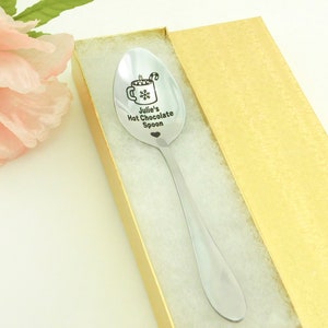 May include: A silver spoon with a personalized inscription that reads "Julie's Hot Chocolate Spoon" and a small heart. The spoon is in a gold gift box.