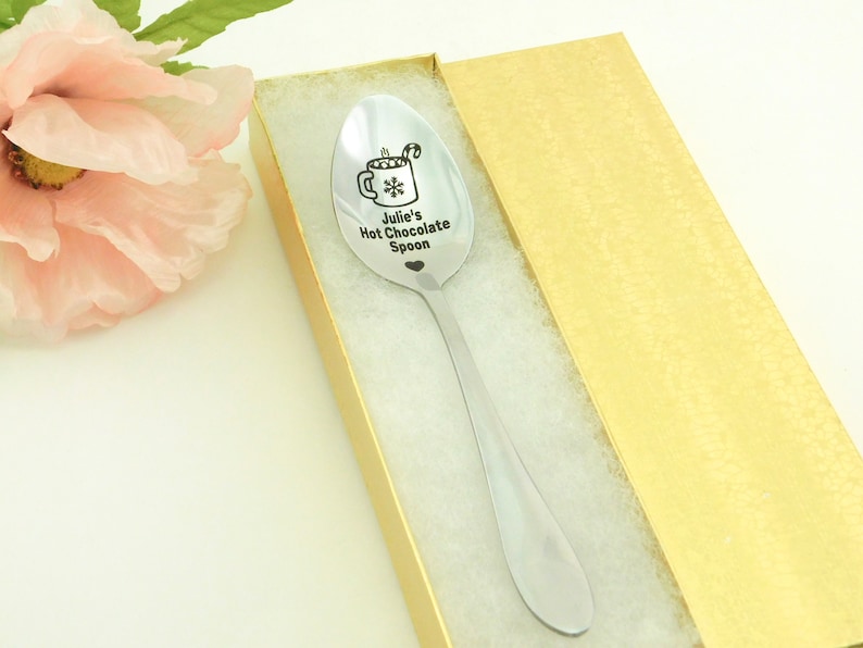 May include: A silver spoon with a personalized inscription that reads "Julie's Hot Chocolate Spoon" and a small heart. The spoon is in a gold gift box.