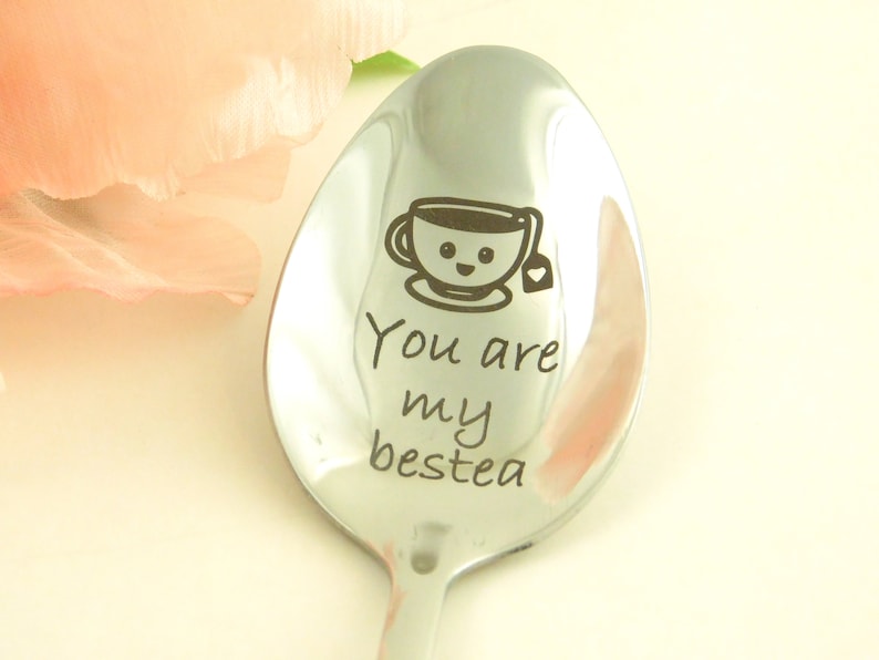 May include: A silver spoon with the text "You are my bestea" engraved on it. A cartoon teacup with a smiley face is above the text.