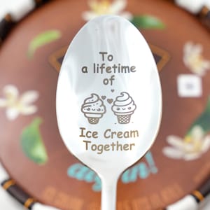 Puede incluir: Una cuchara de plata con la inscripci&oacute;n "To a lifetime of Ice Cream Together" y dos conos de helado de dibujos animados con corazones.