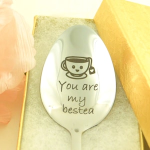 May include: A silver spoon with a smiling teacup and the text "You are my bestea" engraved on it. The spoon is in a gold gift box.