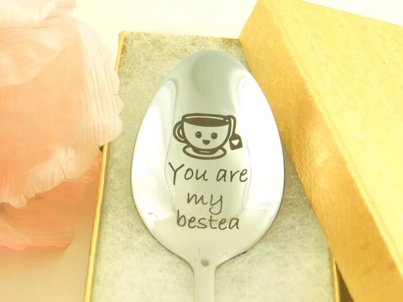 May include: A silver spoon with a smiling teacup and the text "You are my bestea" engraved on it. The spoon is in a gold gift box.