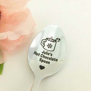 May include: A silver spoon with a black engraved design of a mug of hot chocolate with marshmallows and a candy cane. The text "Julie's Hot Chocolate Spoon" is engraved below the mug.
