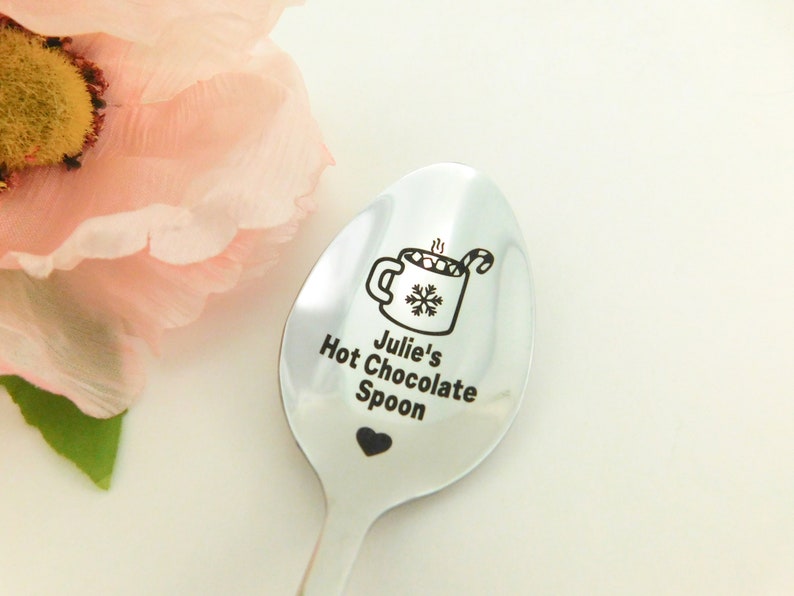 May include: A silver spoon with a black engraved design of a mug of hot chocolate with marshmallows and a candy cane. The text "Julie's Hot Chocolate Spoon" is engraved below the mug.