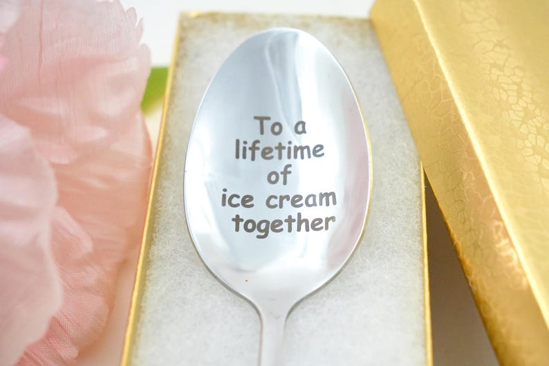 Puede incluir: Una cuchara de plata con la inscripci&oacute;n "To a lifetime of ice cream together". La cuchara est&aacute; en una caja blanca con un borde dorado.