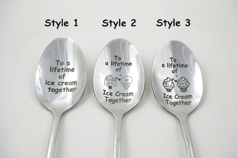 Puede incluir: Tres cucharas de acero inoxidable con diferentes dise&ntilde;os grabados. La primera cuchara dice "To a lifetime of ice cream together". La segunda cuchara dice "To a lifetime of Ice Cream Together" con un cono de helado y una paleta de helado de dibujos animados. La tercera cuchara dice "To a lifetime of Ice Cream Together" con dos cupcakes de dibujos animados.