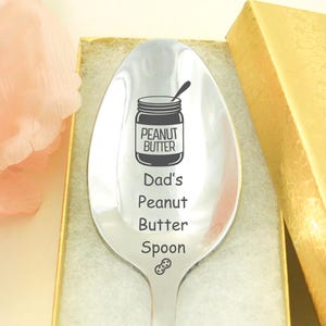 Könnte beinhalten: Ein silberner Löffel mit der Gravur "Dad's Peanut Butter Spoon". Der Löffel zeigt außerdem ein kleines Bild eines Erdnussbutterglases mit der Aufschrift "Peanut Butter".